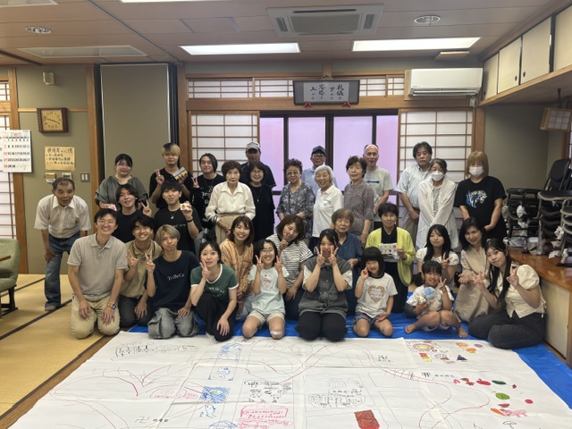 佐味田地区の地図に描かれた「未来のまち」の様子と集合写真