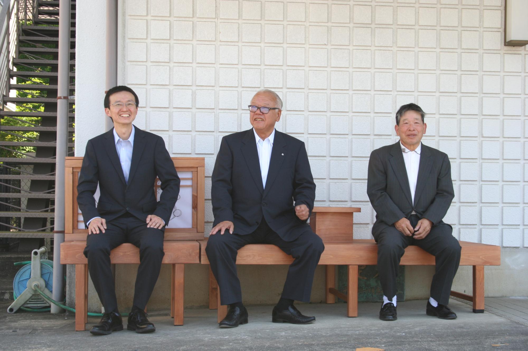 陳先生上本会長森川町長が縁台に腰掛ける様子
